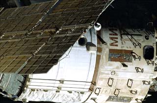 Exterior view of Mir Space Station Base Block and solar array. Red cyrillic letters "Mir" can be seen near top of module.